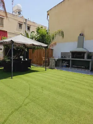 a lawn with an umbrella and a grill at Trudy's home in Nicosia