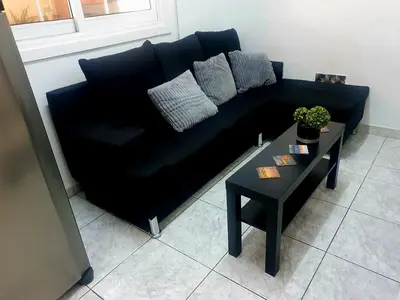 a black couch in a living room with a table at Trudy's home in Nicosia