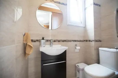 a bathroom with a sink and a toilet and a mirror at Pelagos Villa 8 in Protaras