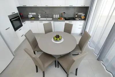 a white kitchen with a white table and chairs at Villa Amazonia - Large Private Pool in Protaras