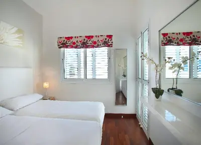 a white bedroom with two beds and two windows at Villa Kos 19 in Protaras