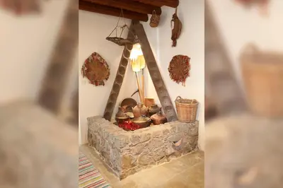 a stone fireplace with pots and pans on a wall at Kalopanayiotis Cottage in Kalopanayiotis