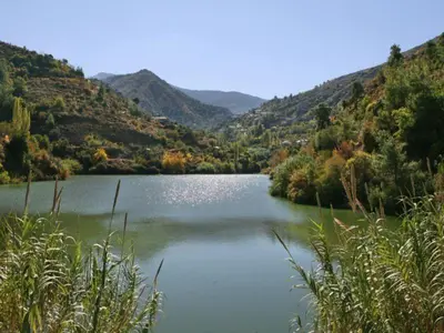 a lake in the middle of a valley with mountains at Kalopanayiotis Cottage in Kalopanayiotis