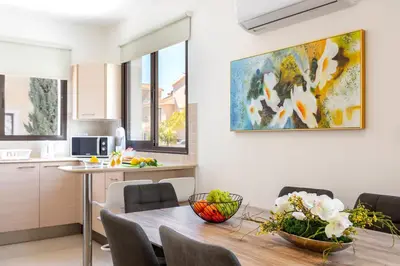a kitchen and dining room with a table and a painting on the wall at Protaras Villa Angela Nefeli in Paralimni