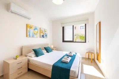 a bedroom with a bed with a blue blanket on it at Protaras Villa Angela Nefeli in Paralimni