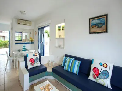 a living room with a blue couch and a kitchen at Villa Julie in Protaras