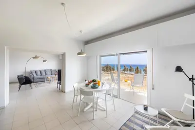 a living room with a table and a view of the ocean at Protaras H2O Seafront Suite in Protaras