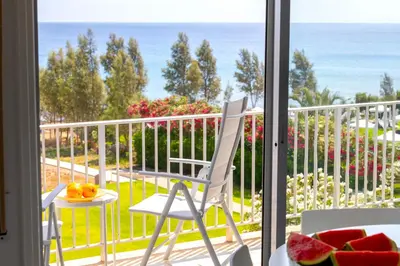 a balcony with a chair and a table and a view of the ocean at Protaras H2O Seafront Suite in Protaras