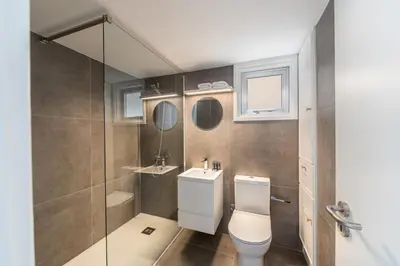 a bathroom with a toilet and a glass shower at Protaras H2O Seafront Suite in Protaras