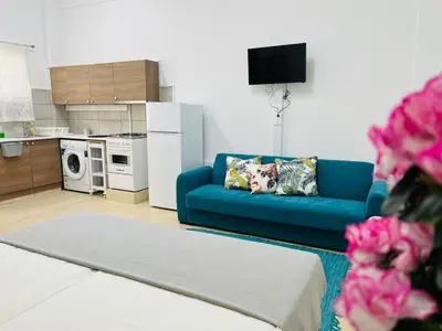 a living room with a blue couch and a kitchen at Larnaca - Studio - Sleeps 4 - Garden - Parking in Larnaka