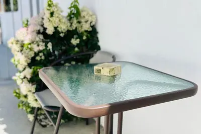 a glass table with a box on it next to flowers at Larnaca - Studio - Sleeps 4 - Garden - Parking in Larnaka