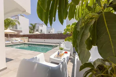 a patio with white chairs and a swimming pool at Nissini villa in Ayia Napa