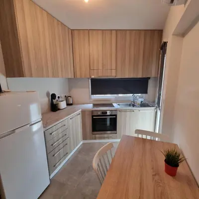 a kitchen with a wooden table and a white refrigerator at SC_apartments in Kato Pyrgos