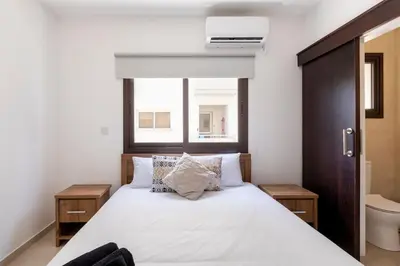 a bedroom with a bed with white sheets and a window at Epicurian Residence in Nicosia
