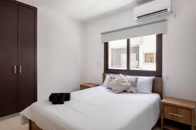 a bedroom with a white bed with a window at Epicurian Residence in Nicosia