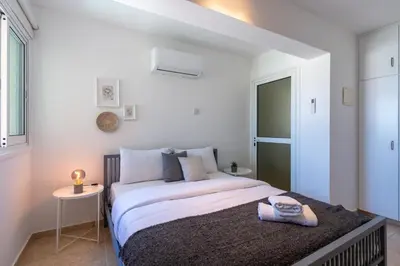 a white bedroom with a large bed and a window at Chloris 3- Bedroom Apartment W/Pool in Larnaca in Larnaka