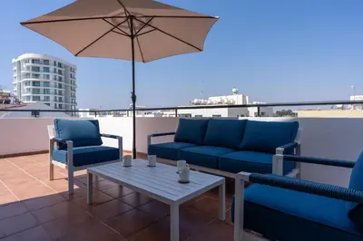 a patio with couches and a table and an umbrella at Chloris 3- Bedroom Apartment W/Pool in Larnaca in Larnaka