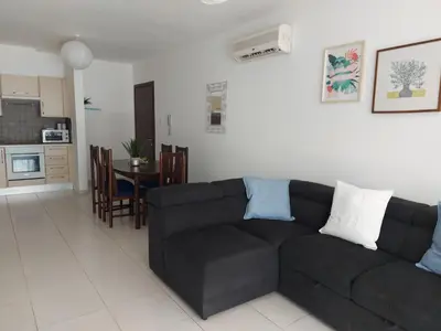 a living room with a black couch and a kitchen at Pyla Palms Resort B1 - 1 in Larnaka