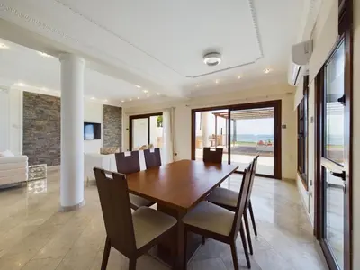 a dining room with a wooden table and chairs at Fabulous beach front house with pool in Larnaka