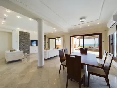 a dining room with a table and chairs and a couch at Fabulous beach front house with pool in Larnaka