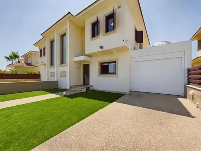 a house with a green lawn in front of it at Fabulous beach front house with pool in Larnaka