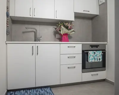 a kitchen with white cabinets and a sink at Lovely Studio by the Beach in Voroklini