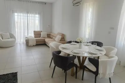 a white living room with a table and chairs at Tereza's House in Ayvaryara
