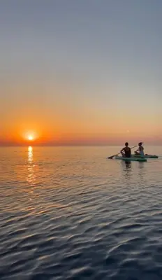 two people on a boat in the water at sunset at Quiet kykladesAG10/near the beach, Paralimni in Paralimni