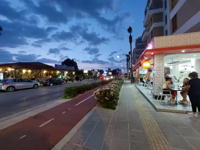 a city street with people sitting at tables on a sidewalk at Beach Serenity Studio on Makenzy in Larnaka