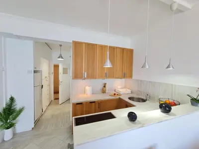 a kitchen with white counters and wooden cabinets at Beach Serenity Studio on Makenzy in Larnaka