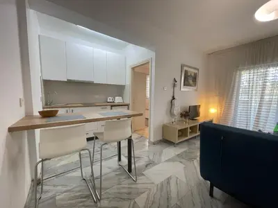 a kitchen with white cabinets and a counter and chairs at Nicosia Downtown Cozy in Nicosia