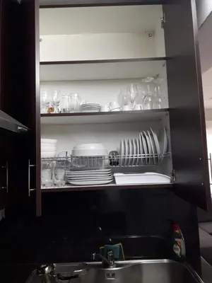 a kitchen cabinet with plates and dishes on a shelf at A MODERN APARTMENT FOR YOU in Nicosia