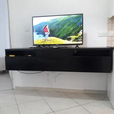 a flat screen tv sitting on top of a black entertainment center at A CHEERFUL APARTMENT in a popular area in Pallouriotissa