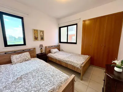 a bedroom with two beds and two windows at Mackenzie apartment 301 in Larnaka
