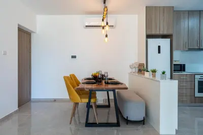 a kitchen and dining room with a table and yellow chairs at Flair - 1-Bedroom Apartment & Balcony in Larnaca in Larnaka