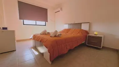 a bedroom with a bed with an orange bedspread and a window at STAY Sand Flat in Paralimni