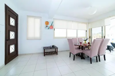 a dining room with pink chairs and a table at Villa Anna Maria, Kapparis in Paralimni