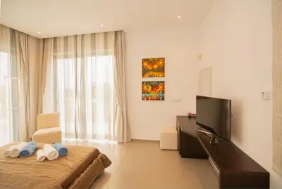 a bedroom with a bed and a tv and a window at Seafront Villa Layla by Ruidoso Luxury in Ayia Napa