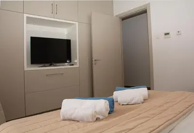 a bedroom with a tv and a bed with towels at Seafront Villa Layla by Ruidoso Luxury in Ayia Napa
