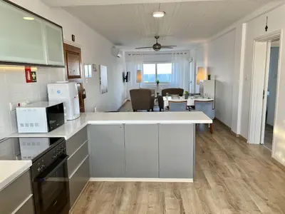 a kitchen with white counter tops and a living room at Seaview Beach Apartment Dasoudi in Limassol