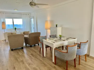 a dining room with a white table and chairs at Seaview Beach Apartment Dasoudi in Limassol