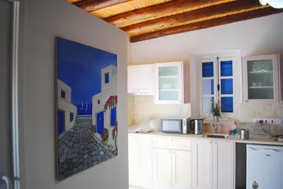 a kitchen with white cabinets and a painting on the wall at To Archontiko tis Anastasias in Athienou