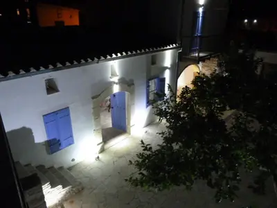 a man standing in front of a white building with blue doors at To Archontiko tis Anastasias in Athienou