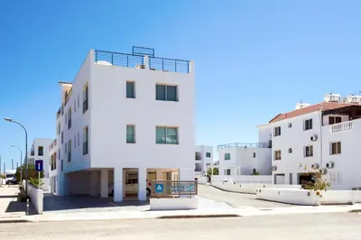 a white building with a sign in front of it at Sea View APT*Spacious balcony*200m to the Beach in Paralimni