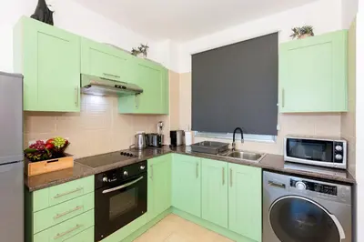 a green kitchen with a sink and a dishwasher at Sea View APT*Spacious balcony*200m to the Beach in Paralimni