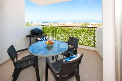 a table with chairs and a bowl of fruit on a balcony at Sea View APT*Spacious balcony*200m to the Beach in Paralimni