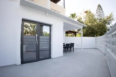 an outdoor patio with a glass door and chairs at Phaedrus Living: Luxury Mackenzie Flat in Larnaka