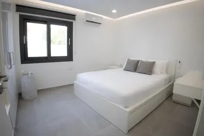 a white bedroom with a white bed and a window at Phaedrus Living: Luxury Mackenzie Flat in Larnaka