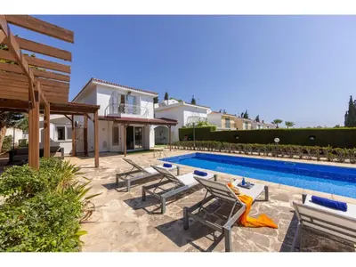 a swimming pool with chaise lounge chairs next to a house at Protaras Apollon Seaside Villa in Protaras