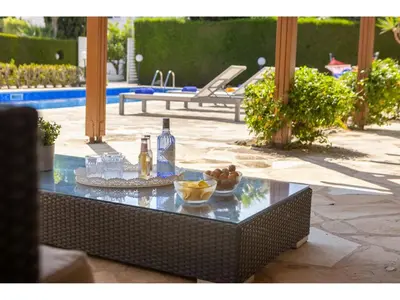 a glass table with drinks and a bowl of fruit on it at Protaras Apollon Seaside Villa in Protaras